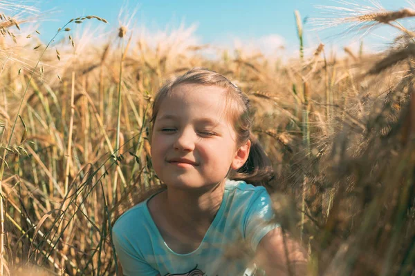 Die Natur genießen. Nahaufnahme eines Mädchens auf einem Feld mit goldenen Stacheln in hellen Sonnenstrahlen im Sommer — Stockfoto