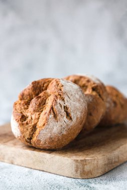 Tahta bir tahtanın üzerinde tam tahıldan ya da çavdar unundan yapılmış yuvarlak taze çörekler var. Avrupa 'da geleneksel pişmiş yiyecekler. Mesajın için yer aç. Fırın, fırın ürünleri üretimi