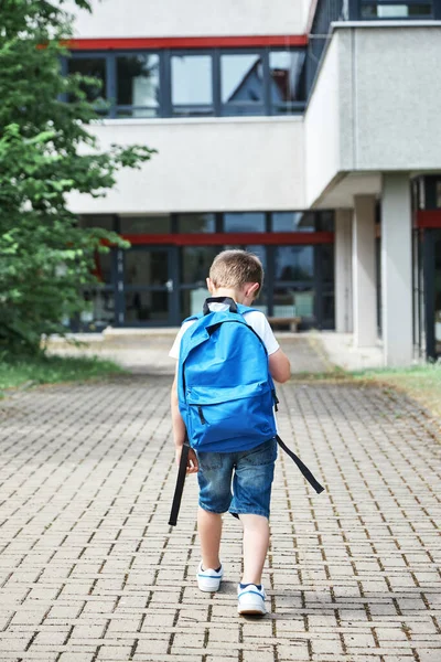 Back to school. Adorable Caucasian boy with blue backpack goes to school in first grade after summer vacation. — Fotografia de Stock