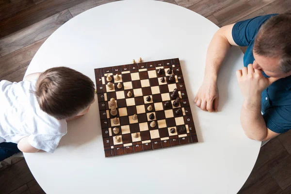 View from above Dad and son are playing a board game of chess. Time and games with children. Logic and strategy game. Authentic moments from real life — Stock Photo, Image
