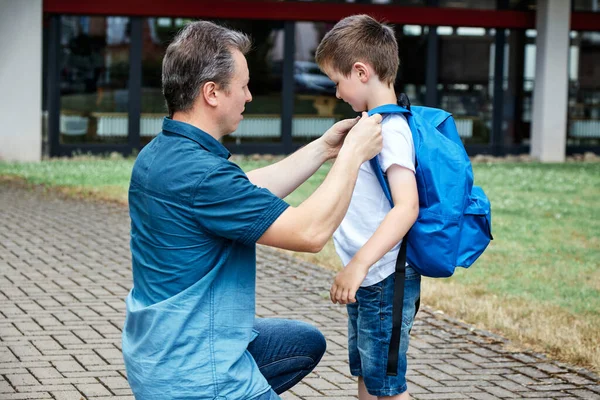 Dad, dad puts a blue backpack on his son. Parents accompany their children to school, first grade. Back to school after summer break — Stock Photo, Image