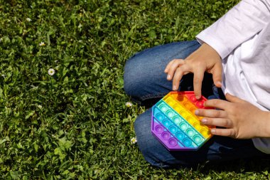 Sokakta yeni bir oyuncakla oynayan bir çocuğun yakın plan fotoğrafı. Patlat ya da basit bir gamzesi olsun. İnce motor becerilerin geliştirilmesi ve içsel stresin serbest bırakılması için moda oyuncaklar