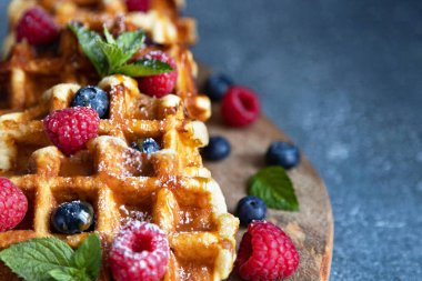 Taze meyve suyuyla süslenmiş taze Belçika waffleları. Bir kafede tatlı. Tatlı yemek.