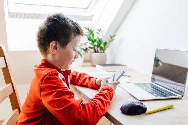 Çocuk gülümsüyor, akıllı bir telefonla meşgul oluyor, ekran zamanını ve dijital öğrenimi yansıtıyor