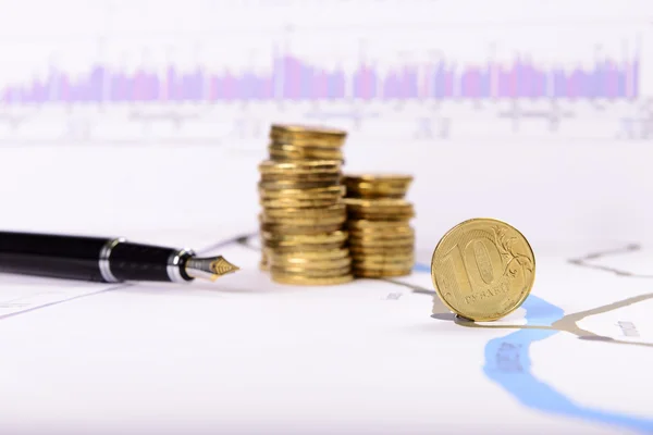 Pen and coins on the background of graphs and charts — Stock Photo, Image