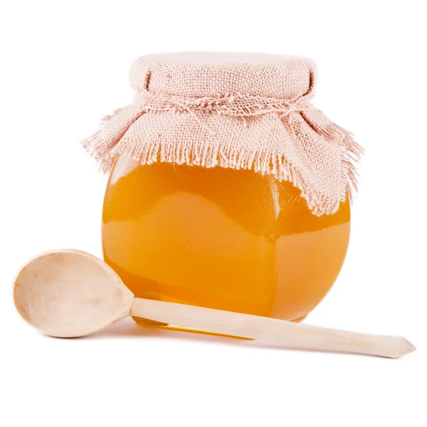 Tarro de miel y cuchara sobre un fondo blanco — Foto de Stock