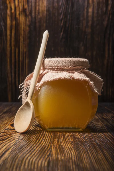 Tarro de miel y cuchara sobre un fondo de madera — Foto de Stock
