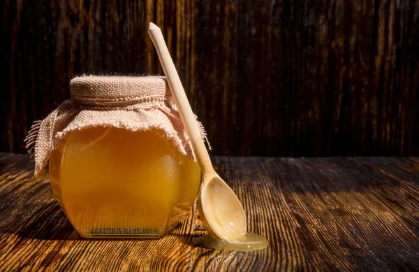 Vaso di miele e cucchiaio su fondo di legno — Foto Stock