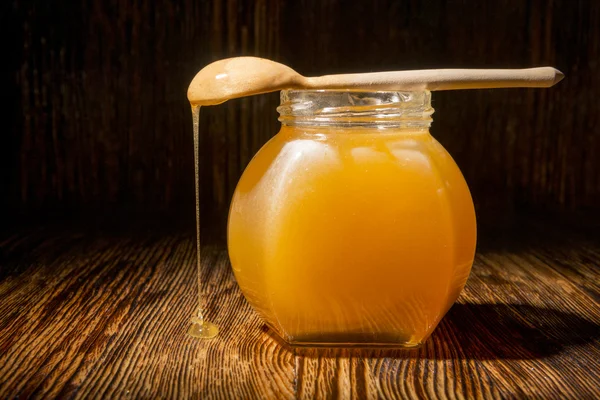 Glas Honig und Löffel auf einem hölzernen Hintergrund — Stockfoto