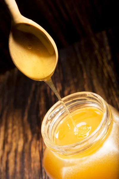 Vaso di miele e cucchiaio su fondo di legno — Foto Stock