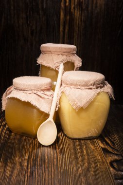 Bal ve kaşık ahşap arka plan üzerinde üç kavanoz