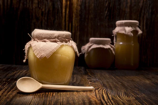 Tre vasetti di miele e cucchiaio su fondo di legno — Foto Stock
