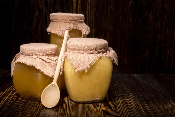 Drie potten van honing en lepel op een houten achtergrond — Stockfoto