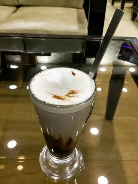 High angle shot of a cold coffee put on the table and ceiling light reflections down.