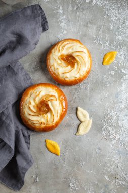 İki taze çörek, arka planda bir masada süzme peynir.