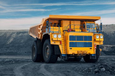 Kömür madeninde büyük bir taş ocağı kamyonu. Kamyona kömür yüklüyorlar. Minerallerin taşınması için maden ekipmanları.