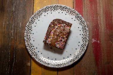 Lezzetli çikolatalı kek dilimi. Üstüne de ahşap mutfak kapağı serpiştirilmiş.