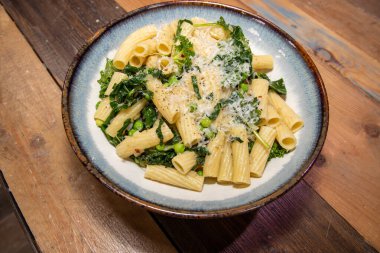 Lezzetli bir tabak bezelyeli ve otlu üstü rendelenmiş peynirli makarna..