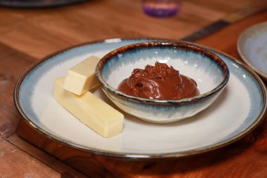 Tahta bir tepside bir tabak peynir ve çikolata.