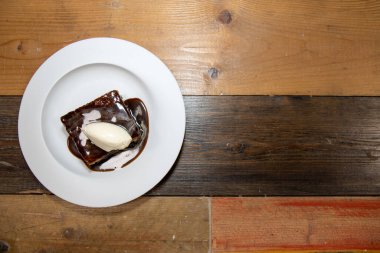 Beyaz bir tabak lezzetli çikolatalı puding kremalı ve çikolatalı kek ahşap mutfak kapağında.