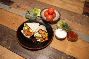 Guacamole soslu lezzetli tavuk fajitaları ve ahşap mutfak tepesinde ekşi krema.