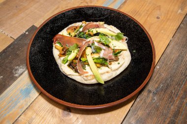 Tahta mutfak tepesinde Humus, Mantar, Serrano Jambon ve Avokado ile nefis bir tabak mısır gevreği.