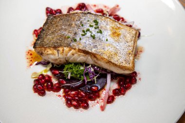 Lezzetli bir tabak balık, kış salatası ve nar.