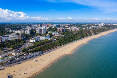 Bournemouth plajının ve şehir merkezinin güzel güneşli bir yaz gününde çekilen insansız hava aracı fotoğrafı İngiliz güneşli plajındaki kumsaldaki insanları gösteriyor.