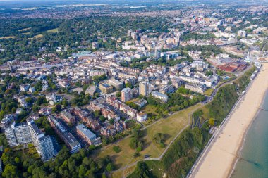 Bournemouth sahilinin ve şehir merkezinin hava aracı fotoğrafı güzel güneşli bir günde sahildeki otelleri, konuk evleri ve deniz kenarındaki evleri gösteriyor.