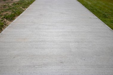 Yanında çimen olan beton bir yol.