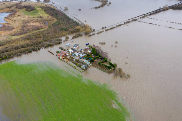 Aerial drone photo of the town of Allerton Bywater near Castleford in Leeds West Yorkshire showing the flooded fields and farm house from the River Aire during a large flood after a storm.