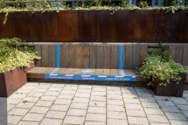 Leeds UK, 12 Ağustos 2020: Leeds Rıhtımı 'nda bir bank, üzerinde 2 metre arayla oturmaları gerektiğini hatırlatan çıkartmalar var ve sadece 1 kişi ya da 1 çift yazıyor.