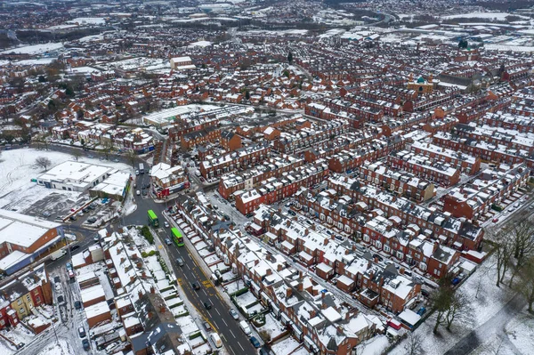 Aerial photo of a snowy day in the city of Leeds in the UK, showing rows of terrace houses with snow covered roofs in the Village of Beeston in the winter time