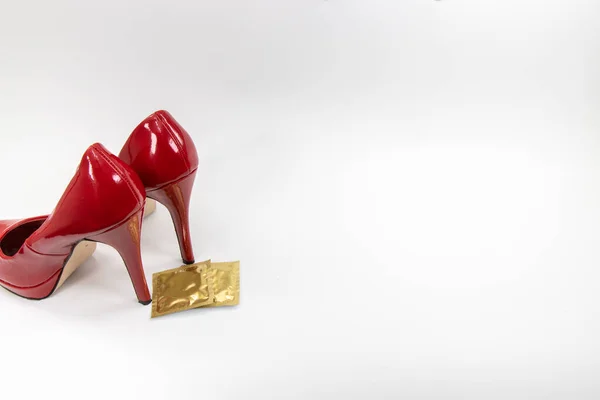 一双经典的性感高跟鞋高跟鞋 白色背景的金色避孕套封套 — 图库照片