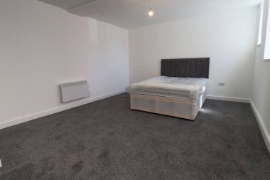 Yeni dekore edilmiş tipik bir İngiliz yatak odası. Geniş yatağı, beyaz duvarları ve gri halısı var.