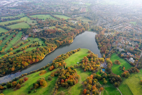 Aerial photo in autumn showing the beautiful autumn fall colours of a park in Leeds known as Roundhay Park in West Yorkshire UK, showing a typical British park and woods along side a lake.
