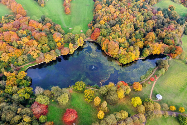 Aerial photo in autumn showing the beautiful autumn fall colours of a park in Leeds known as Roundhay Park in West Yorkshire UK, showing a typical British park and woods along side a lake.