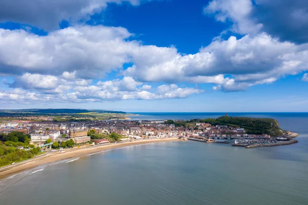 İngiltere 'nin Doğu Yorkshire kentindeki Scarborough şehir merkezinin hava fotoğrafı güneşli bir yaz gününde kıyıları ve limanı teknelerle ve Scarborough Kalesi' yle gösteriyor.