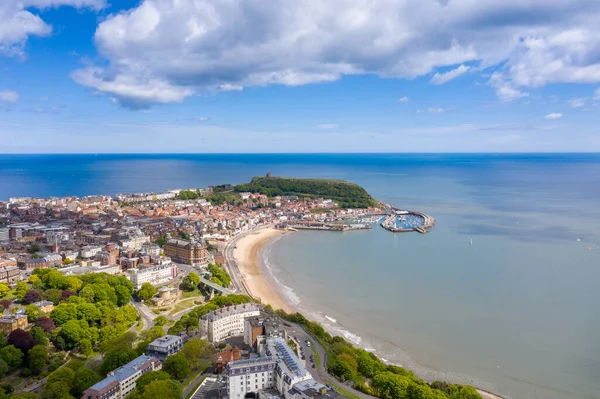 Aerial photo of the town centre of Scarborough in East Yorkshire in the UK showing the coastal beach and harbour with boats and the Scarborough Castle on a bright sunny summers day