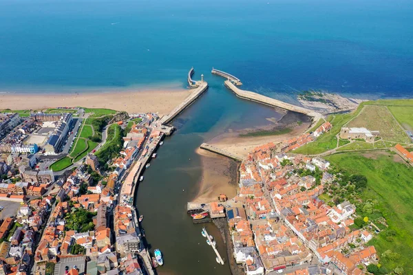 Aerial photo of the beautiful town of Whitby in the UK in North Yorkshire in the UK showing the beach and harbour on a hot sunny summers day