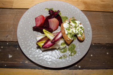 Lezzetli bir tabak vejetaryen yemeği pancar kökü keçi peynirli tost ve ahşap mutfak masasında sos.