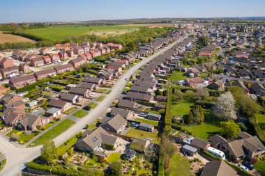 İngiltere 'nin Leeds West Yorkshire kentindeki Kippax kasabasının hava fotoğrafı güneşli bir yaz gününde gökyüzünde beyaz kabarık bulutlar olan konut evlerini gösteriyor..