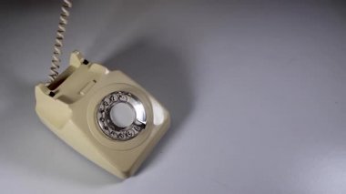 Zarif bir kadının eli ahşap bir arka plana 70 'lerin ve 80' lerin modası bir telefon ahizesi yerleştirip telefon konseptiyle flört ediyor.