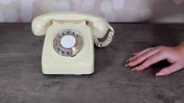 Zarif bir kadının eli 70 'li ve 80' li yılların modası bir telefon ahşap arka plan, retro ofis telefonu konseptörüne bağlanıyor.