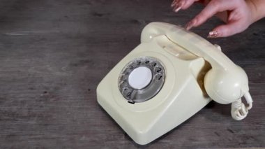 Zarif bir kadının eli 70 'li ve 80' li yılların modası bir telefon ahşap arka plan, retro ofis telefonu konseptörüne bağlanıyor.