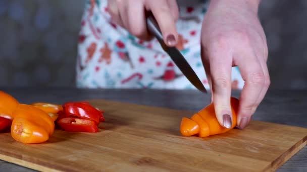 Una Mujer Una Cocina Cortando Pimientos Anaranjados Rojos Una Tabla — Vídeos de Stock