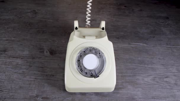 エレガントな女性の手が取り上げられ 木製の背景に古いヴィンテージ70年代と80年代のスタイルのロータリー電話受信機を置く レトロなオフィスの電話のコンセプト — ストック動画