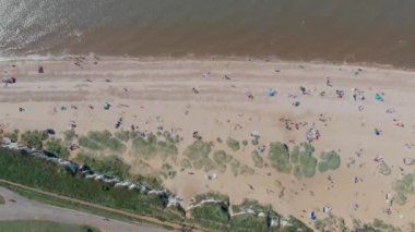 İngiliz sahil kasabası Hunstanton Norfolk 'un hava görüntülerinde plajın güney ucunda güneşlenen ve oynayan insanlar ve aileler görülüyor..