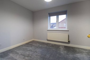 Yepyeni, modern bir İngiliz evi. Yeni yapılmış ve dekore edilmiş bir yatak odası ve yeni dikilmiş gri bir halı.