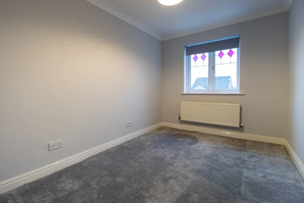 A brand new modern British home showing a brand newly built and decorated bedroom with a newly fitted grey carpet